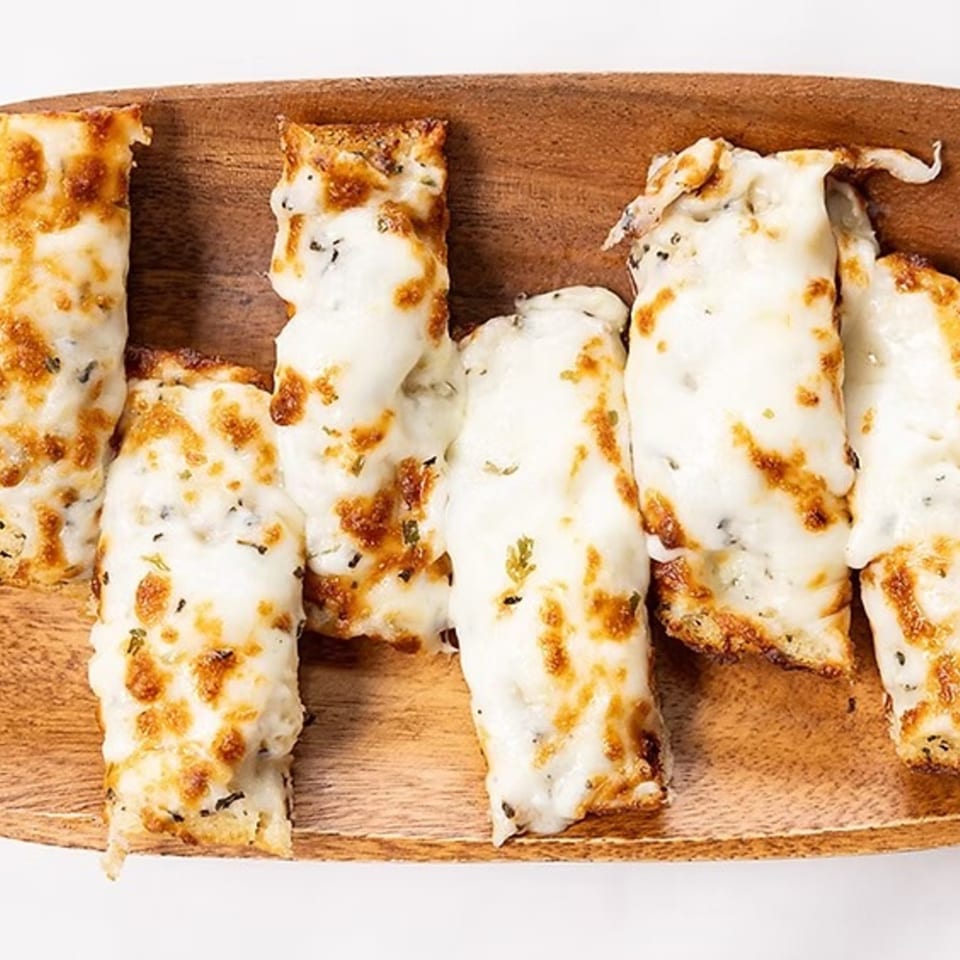 Cheesy breadsticks with melted mozzarella and herbs on a wooden board from Bob Cantu's Pizza.