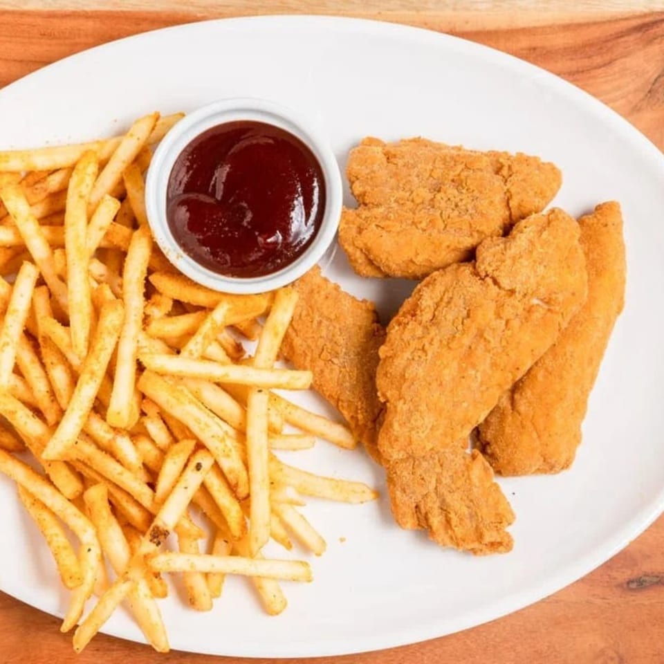 Crispy chicken tenders and golden french fries with a side of ketchup on a white plate.