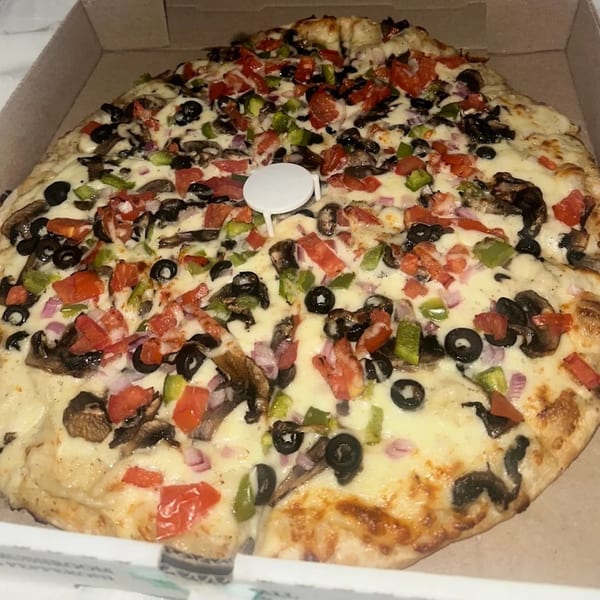 Bob Cantu's Pizza with white sauce, mushrooms, olives, green peppers, and tomatoes in a box.