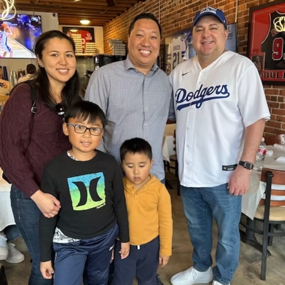 Two adults and two children posing for a photo inside Bob Cantu's Pizza and Sports Bar.