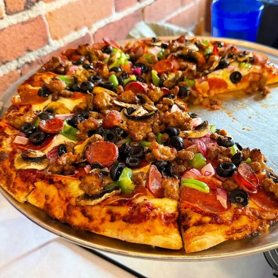 A Bob Cantu's Pizza and Sports Bar pizza with pepperoni, sausage, olives, and peppers.