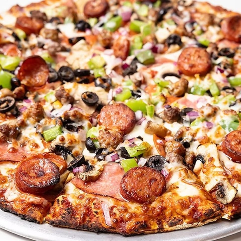 Close-up of a Bob Cantu's Pizza with pepperoni, sausage, olives, green peppers, and mushrooms.