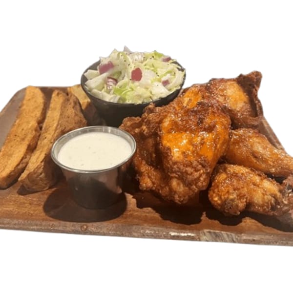 Crispy chicken wings, a side salad, garlic bread, and ranch dressing on a wooden board.